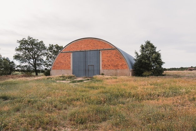 Agricultural warehouse in the field surrounded by trees on a cloudy day