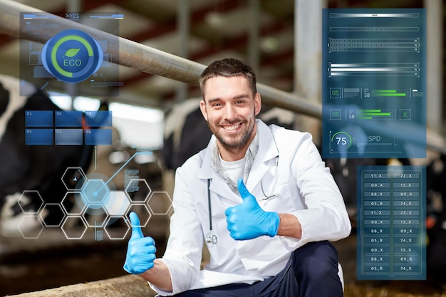 agriculture industry, people and animal husbandry concept - veterinarian or doctor and cows in cowshed on dairy farm showing thumbs up hand sign