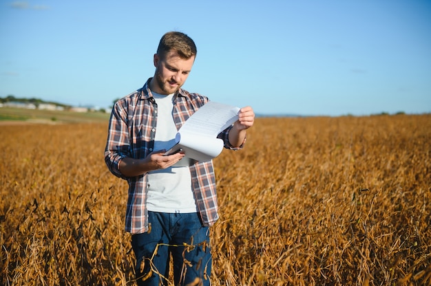 Агроном проверяет урожай сои на сельскохозяйственном поле - концепция Agro - фермер на плантации сои на ферме.