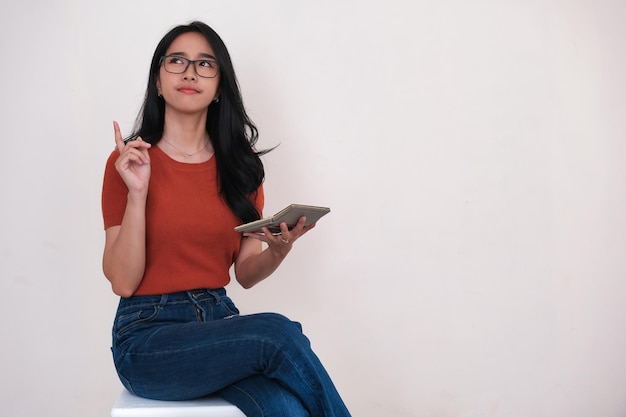 Photo aha facial expression of an asian woman holding a small calculator in her hand