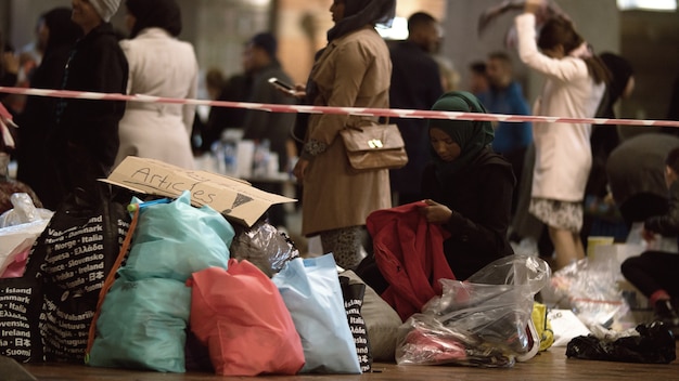 Photo aid worker distributing clothes at charity collecting point in copenhagen railroad station