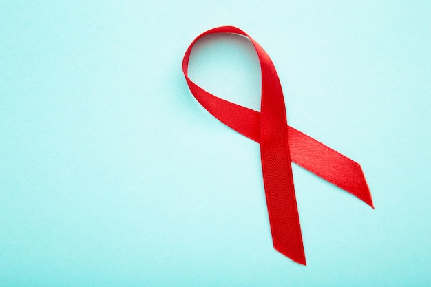 aids awareness red ribbon on blue surface