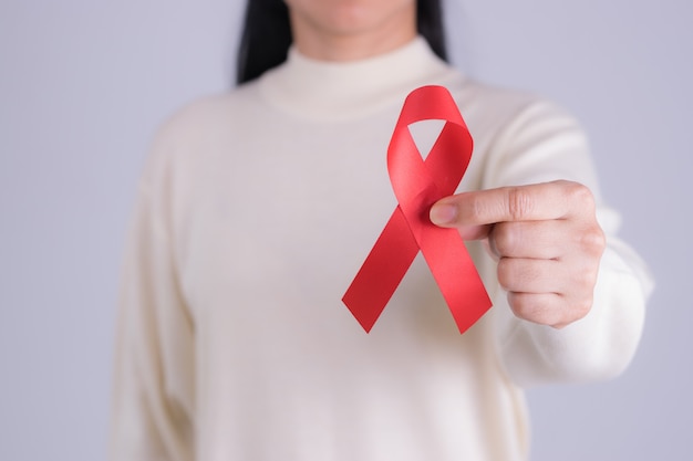 Aids red ribbon in woman's hand for World aids day or  HIV. Aids awareness month concept. Copy space.