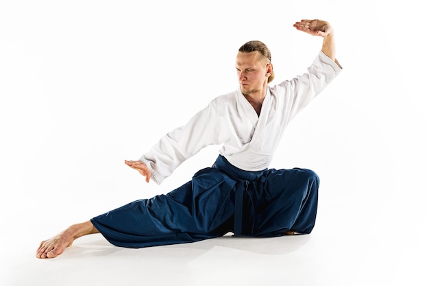 Foto aikido-meester beoefent verdedigingshouding. gezonde levensstijl en sport concept. man met baard in witte kimono op witte achtergrond. karate man met geconcentreerd gezicht in uniform.