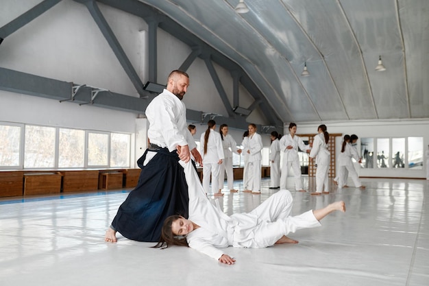 Aikido sensei and teenage female student training throwing and falling. Martial arts practicing concept