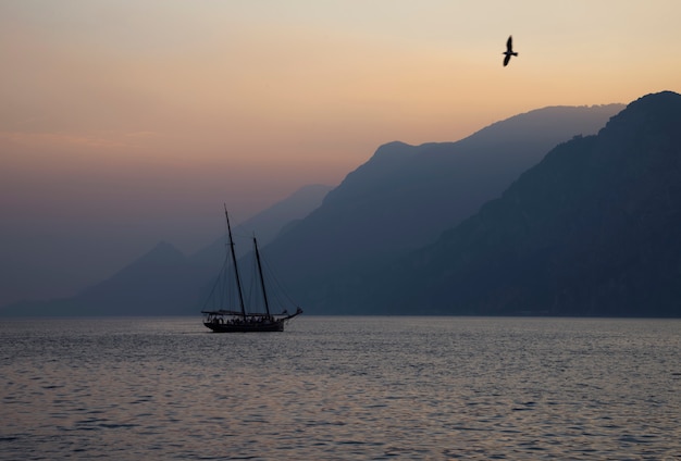 Ailboat sailing at sunset on the background of a mountain range