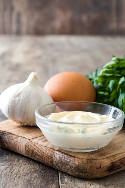 Aioli sauce and ingredients on wooden table