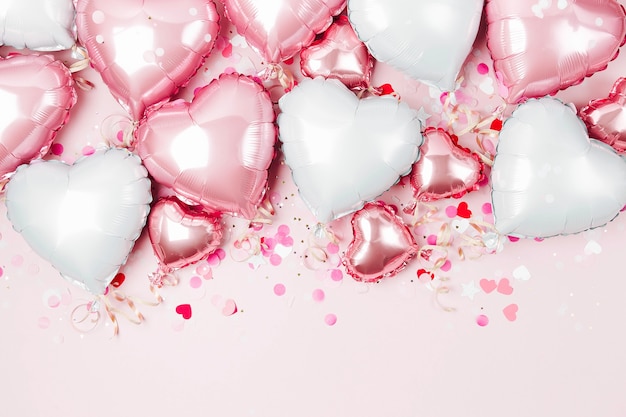 Mongolfiere di lamina a forma di cuore su sfondo rosa pastello. concetto di amore. celebrazione delle vacanze. decorazione di san valentino o matrimonio/addio al nubilato. palloncino metallico