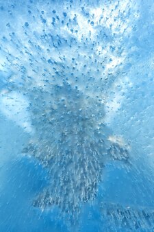 Le bolle d'aria che salgono dal fondo si sono congelate nel ghiaccio blu trasparente modello e consistenza del ghiaccio