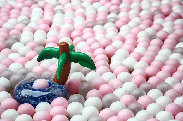 プラスチック製のボールのおもちゃのプールに、空気ココナッツの木の風船が浮かんでいます。カラフル。