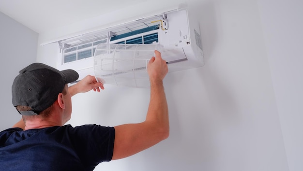 Air conditioner repair and maintenance The technician removes the filter of the indoor unit for cleaning