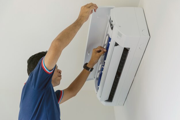 Ремонтники кондиционера в синей форме проверяют и ремонтируют висящий на стене воздух.