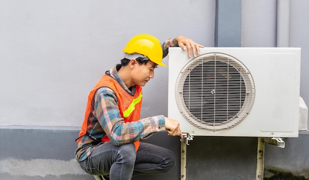 The air conditioner technician Uses a wrench to tighten the nut of the air compressor.