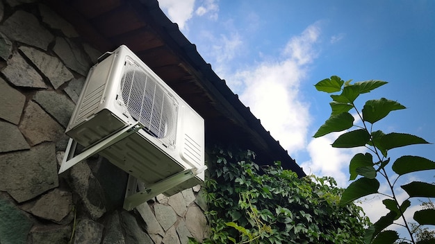 Air conditioner unit on a stone wall of the facade of a house outside Climate control of a country house