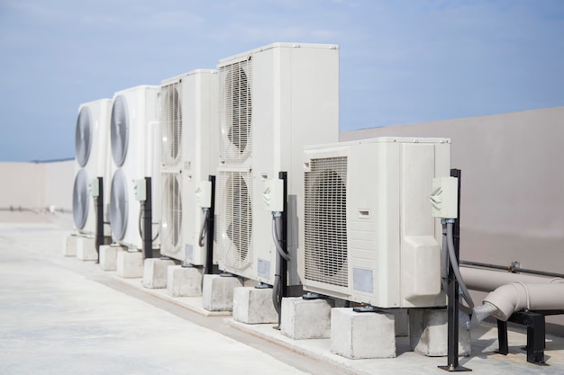 Air conditioning (HVAC) on the roof of an industrial building with blue sky and clouds.