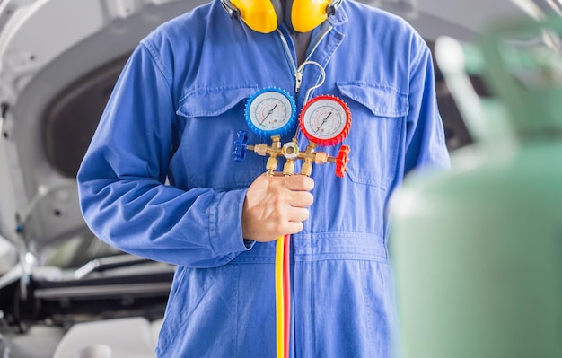 Фото Техник по ремонту кондиционера держит инструмент монитора для проверки и ремонта системы кондиционера автомобиля