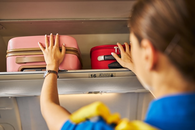 Air hostess fixating two bags on a shelf