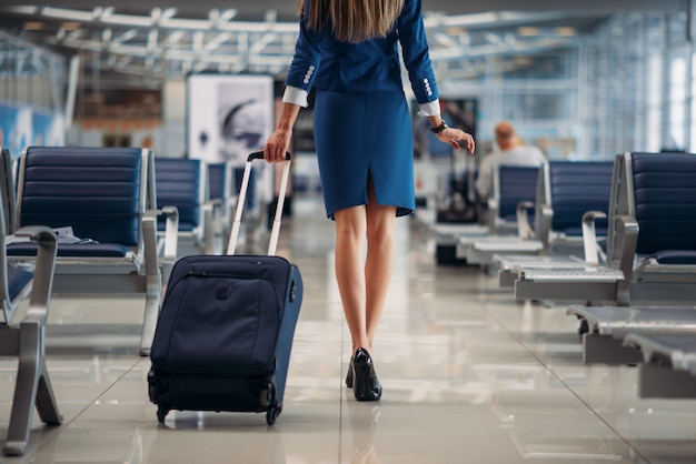 Hostess di volo tra le file di sedili in aeroporto