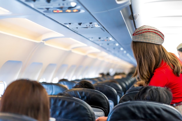 air hostess in red uniform services and checks for all correct