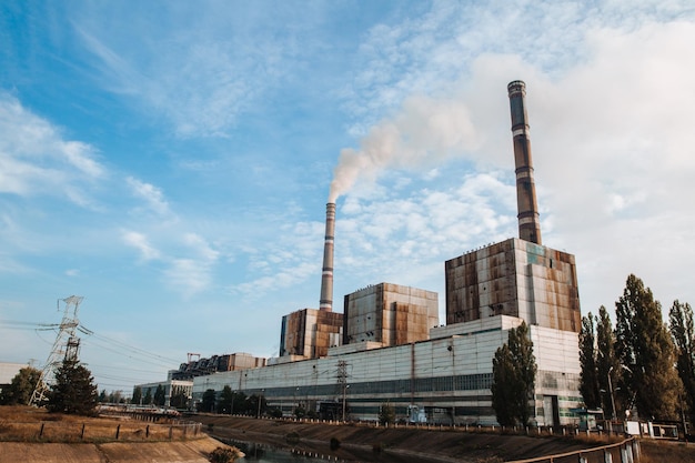 大気汚染工場のパイプは空の背景の煙突から煙を出します