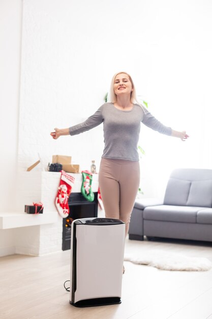 Air purifier in a living room, woman working with laptop with filter for clean room