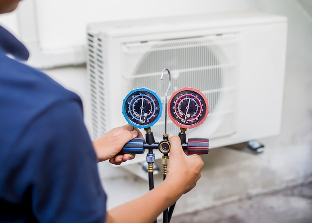 Air repair mechanic using measuring equipment for filling industrial factory air conditioners.