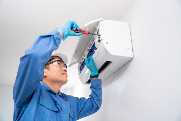 Air technician service repairing and installs air conditioner on white wall Service concept of an air conditioner technician