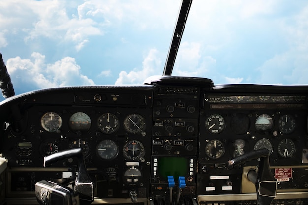 Photo air transport, travel, technology and aviation concept - dashboard in airplane cockpit and view of cloudy sky behind windshield