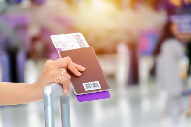 写真 空の旅は最も速く安全な旅行方法ですパスポートを持っている女性の手は旅行チケットをスーツケースに置きます