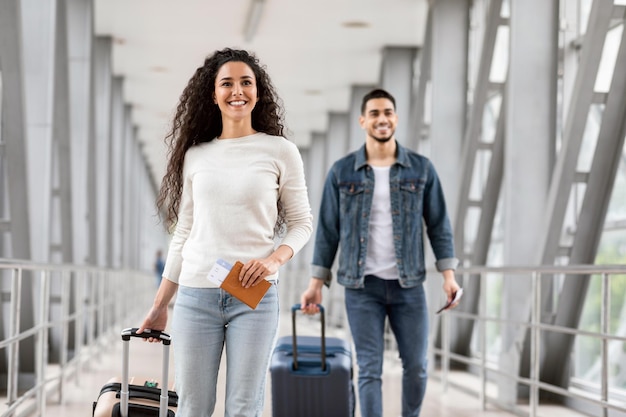 air travels concept happy man and woman walking with suitcases in airport