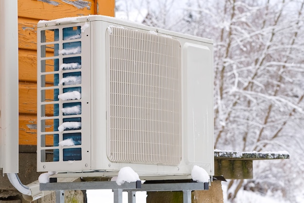 Photo air to water heat pump near an old wooden house in winter.