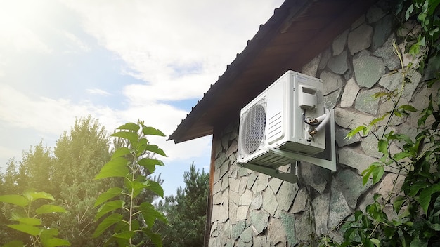 Airconditionereenheid op een stenen muur van de gevel van een huis buiten Klimaatbeheersing van een huis in de voorsteden