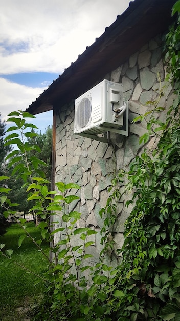Airconditionereenheid op een stenen muur van de gevel van een huis buiten klimaatbeheersing van een privé woonhuis