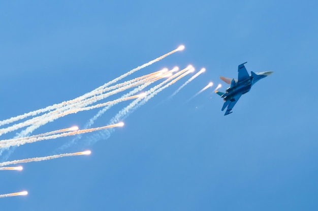 Aircraft fighter flies and shoots heat guns in the blue sky