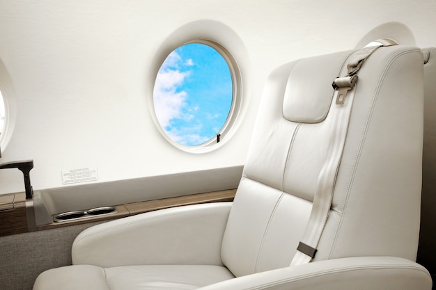 Интерьер самолета (реактивного) бизнес-класса с голубым небом за иллюминатором