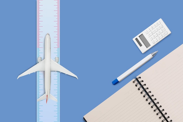 Aircraft model on ruler measure and diary book on blue color background