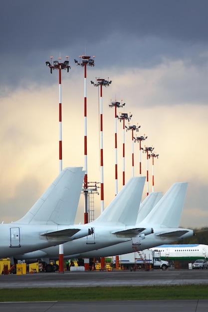 aircraft tails parked at airport apron against  cloudy sky