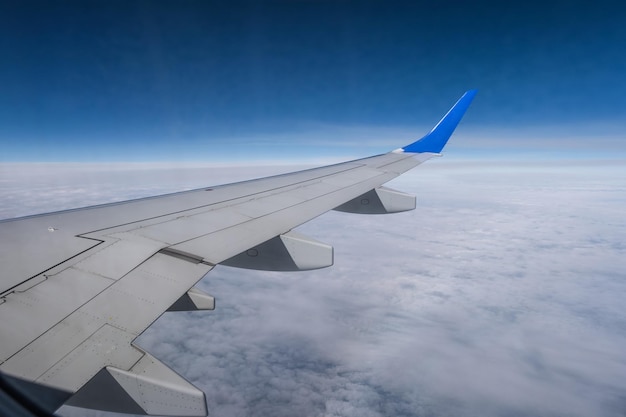 Aircraft wing from the aircraft window overlooking the blue sky and beautiful clouds