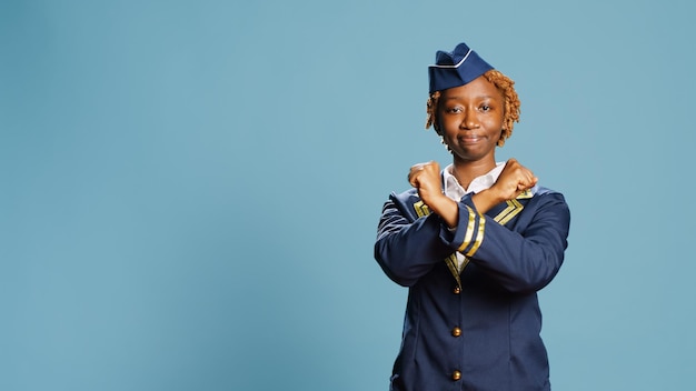 Aircrew member doing refusal gesture and disapproval, saying no with rejection or denial sign with hands. Young air hostess expressing disagreement and disapproval symbol, aviation job.