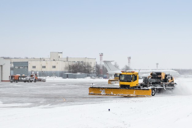 Airfield snow blowers cleaning the area near the airplane hangar at the airport in a severe blizzard