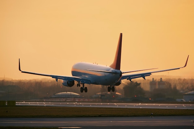 해가 지는 황금빛에 공항 활주로에 착륙하기 위해 접근하는 여객기