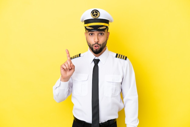 Airplane arab pilot man isolated on yellow background intending to realizes the solution while lifting a finger up