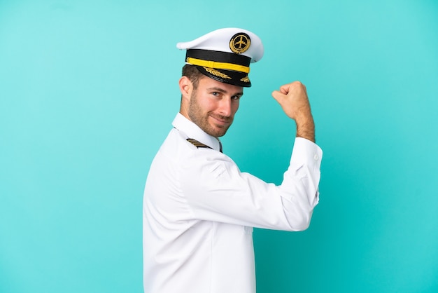 Airplane caucasian pilot isolated on blue background doing strong gesture