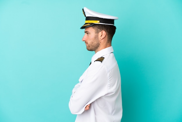 Airplane caucasian pilot isolated on blue background in lateral position