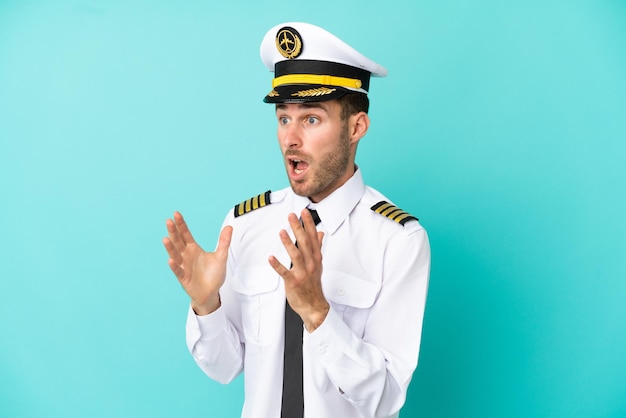 Airplane caucasian pilot isolated on blue background with surprise facial expression