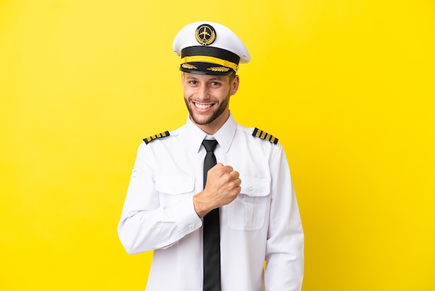 Airplane caucasian pilot isolated on yellow background celebrating a victory