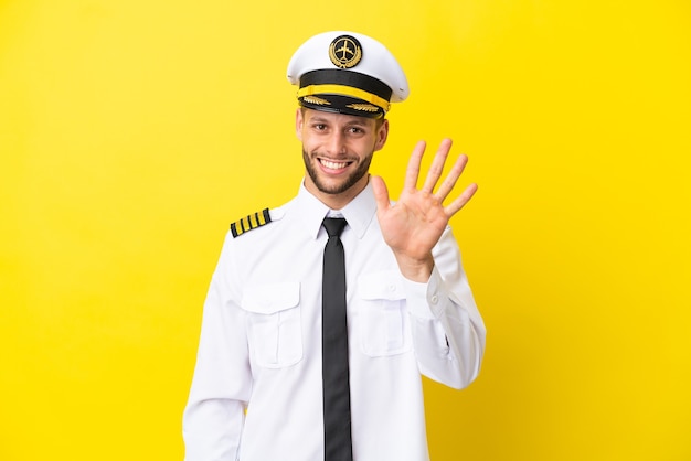 Airplane caucasian pilot isolated on yellow background counting five with fingers