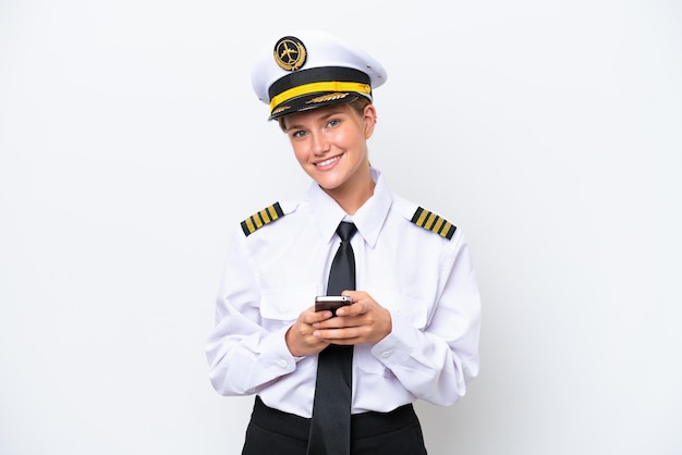 Airplane caucasian pilot woman isolated on white background sending a message with the mobile