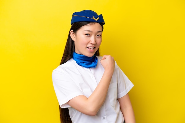 Airplane Chinese woman stewardess isolated on yellow background celebrating a victory