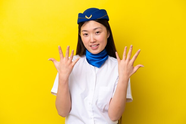 Airplane Chinese woman stewardess isolated on yellow background counting ten with fingers